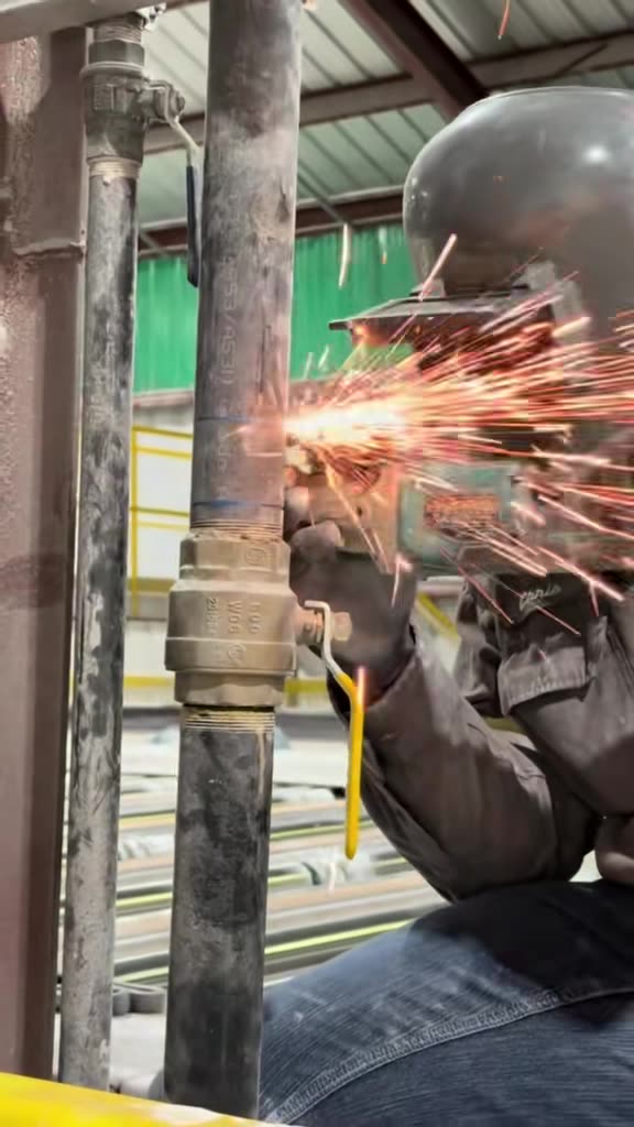 Excel Services tech cutting out a failed pipe section with a grinder