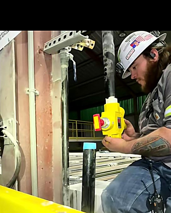 Excel Services tech in hard hat setting a new pneumatic safety valve on plant piping